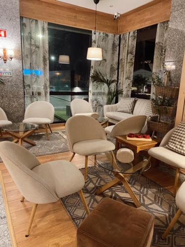a room with white chairs and tables and a room with a window at Hotel Lusitano in Vilar Formoso