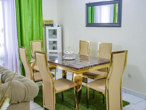 a dining room with a table and chairs at Maxim Hous, Central au Rond point Maetur Bonamoussadi, Fibre Optique, Groupe électrogène, Forage, Parking, Netflix, Canal Sat, Balcon emmenagé in Douala