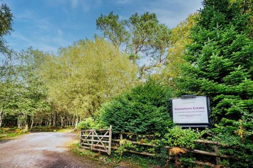 a sign on the side of a road with trees at Ashenhurst, woodland lodge with hot tub for 4 in Oakamoor