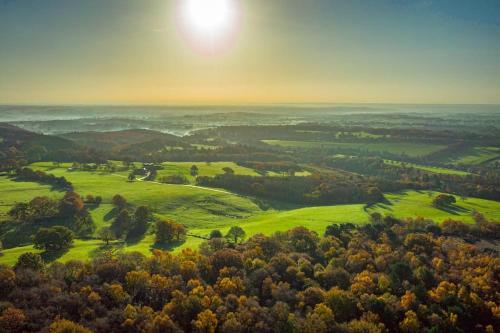 a view of a golf course with the sun in the background at Ashenhurst, woodland lodge with hot tub for 4 in Oakamoor