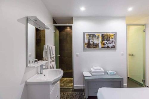 une salle de bain blanche avec un lavabo et un miroir dans l'établissement Appartement cosy près du Marais, à Paris