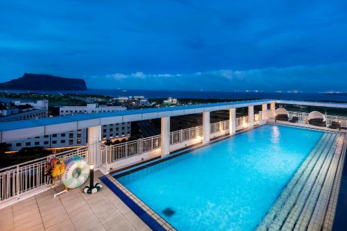a pool on the top of a building at night at The Best Jeju Seongsan in Seogwipo