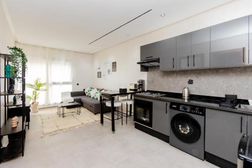 a kitchen with a washing machine and a living room at Appartement cosy et moderne Bouskoura proche Aéroport et Hopital universitaire in Bouskoura