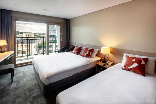 a hotel room with two beds and a window at The Best Jeju Seongsan in Seogwipo