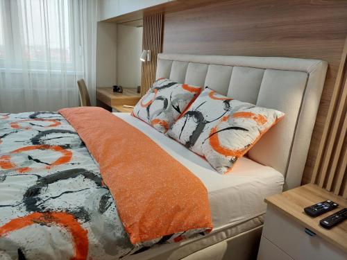 a bedroom with a bed with an orange blanket and pillows at Royal Apartman in Bijeljina