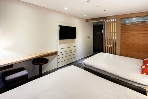 a hotel room with a bed and a tv at The Best Jeju Seongsan in Seogwipo