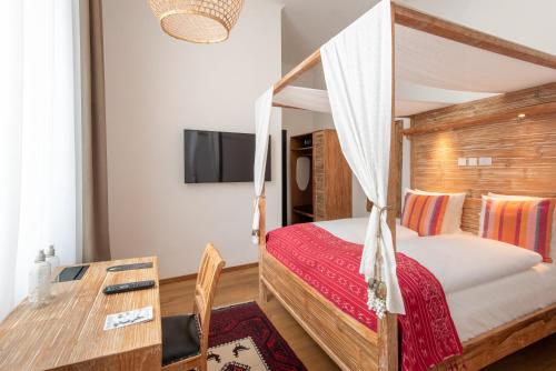 a bedroom with a canopy bed with a desk and a table at Lulu Guldsmeden in Berlin