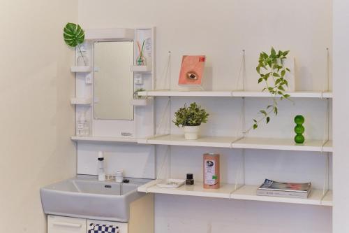a bathroom with white shelves with a sink and a mirror at Kaikai House - Art, Design & Family in Shibuya in Tokyo