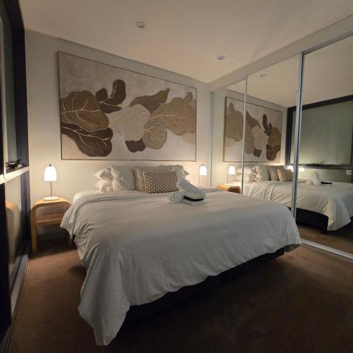 a bedroom with a large white bed and two mirrors at Pristine on Flinders in Melbourne