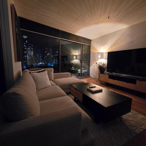 a living room with a white couch and a television at Pristine on Flinders in Melbourne