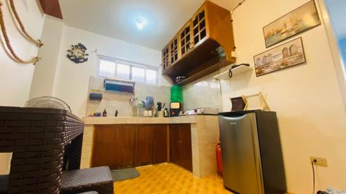 a kitchen with a stainless steel refrigerator and wooden cabinets at The Beach House at Elyu Exclusive Beach Front Villa in Bauang