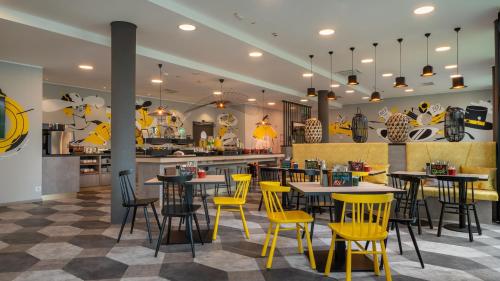 a restaurant with yellow chairs and tables and a kitchen at Holiday Inn - the niu, Fury Aschheim Messe by IHG in Aschheim