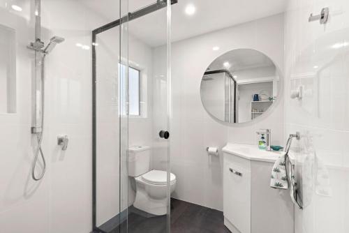 a white bathroom with a shower and a toilet at Callala Bay Gem - Jervis Bay - Pet Friendly Getaway with Spa in Callala Bay