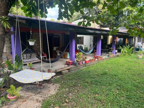 a house with a porch with a swing at Passiflora Backpackers Samara in Sámara