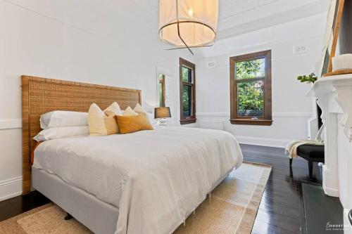 a white bedroom with a large bed and a fireplace at The Waratah House close to town center in Katoomba
