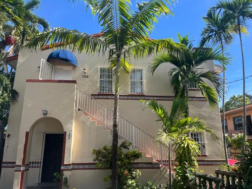a white house with palm trees in front of it at Beds & Sheets little Havana in Miami