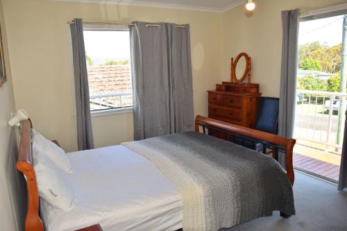a bedroom with a bed and a window with a balcony at Spencer's Cottage - Bring your own linen. in South West Rocks