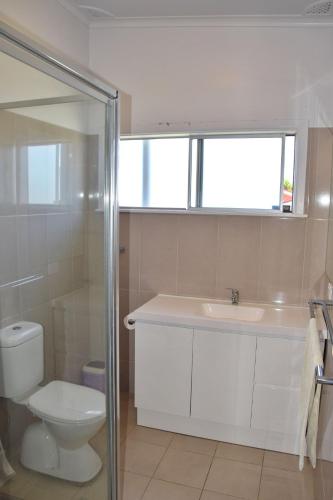 a bathroom with a sink and a toilet and a window at Spencer's Cottage - Bring your own linen. in South West Rocks
