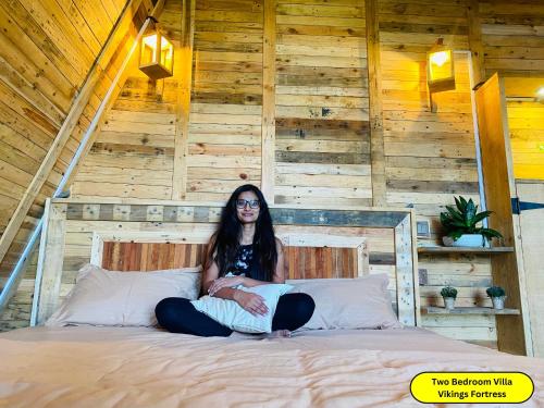 a woman sitting on a bed with a laptop at Hunters Wood Cabins in Nuwara Eliya