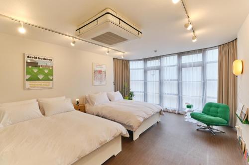 a bedroom with two beds and a green chair at Kaikai House - Art, Design & Family in Shibuya in Tokyo
