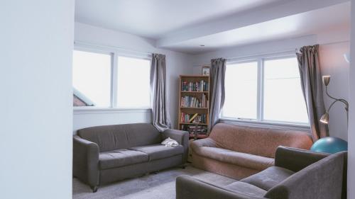 a living room with a couch and a chair and two windows at The Last Resort Hostel in Queenstown