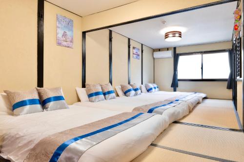 a row of four beds in a room at Kizuna 絆 - 5 Bedding in 2 Japanese-style Bed Rooms, 11 PAX, 30min to USJ, Kaiyukan Aquarium, Namba, Osaka Catsle, and Tsutenkaku Tower, Self-check-in Property, Quiet Neighborhood Stay, Perfect for Families & Business Guests, Extended Stay Perks in Osaka