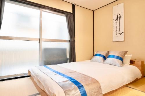a bedroom with a bed and a large window at Kizuna 絆 - 5 Bedding in 2 Japanese-style Bed Rooms, 11 PAX, 30min to USJ, Kaiyukan Aquarium, Namba, Osaka Catsle, and Tsutenkaku Tower, Self-check-in Property, Quiet Neighborhood Stay, Perfect for Families & Business Guests, Extended Stay Perks in Osaka