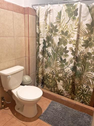 a bathroom with a toilet and a shower curtain at Point Break Santa Teresa in Santa Teresa Beach