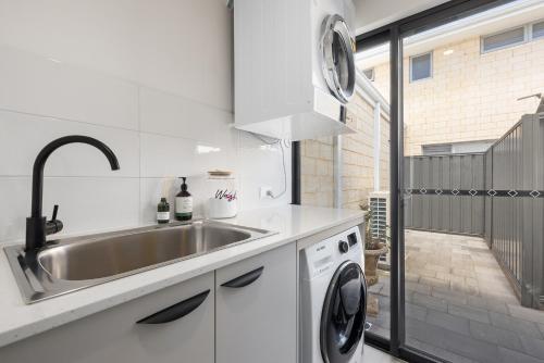 a kitchen with a sink and a washing machine at Family Friendly Close 2 Airport, Optus, Crown & City in Perth