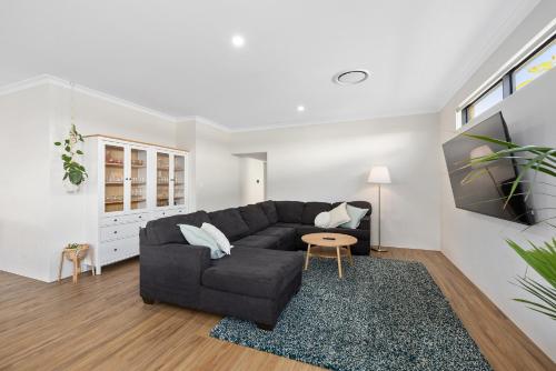 a living room with a black couch and a table at Family Friendly Close 2 Airport, Optus, Crown & City in Perth