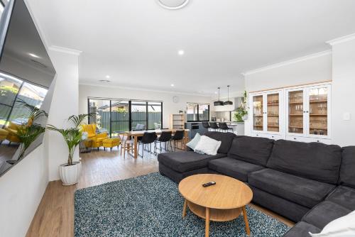 a living room with a black couch and a table at Family Friendly Close 2 Airport, Optus, Crown & City in Perth
