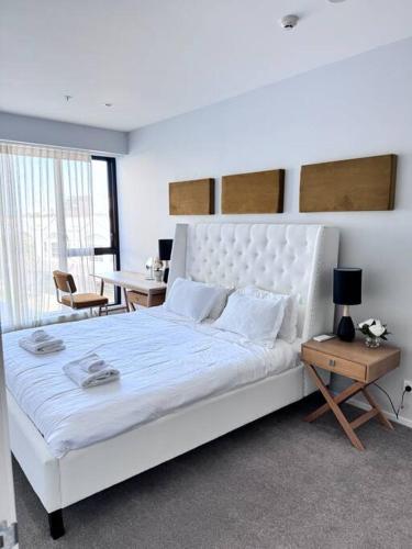 a bedroom with a large white bed and a table at Hereford aparment in Auckland