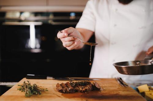 a chef is preparing a steak on a cutting board at Stock Exchange Hotel, Manchester, Autograph Collection in Manchester