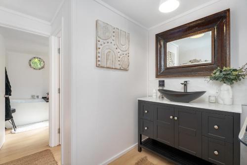 une salle de bain avec un lavabo et un miroir au mur dans l'établissement Hosts on the Coast Bayview Sanctuary, à Whitianga