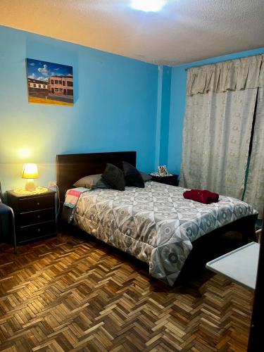 a bedroom with a bed and a blue wall at Amplio y cómodo departamento. in Loja