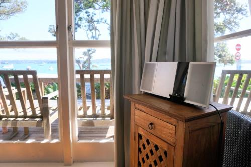 a television on top of a wooden dresser with a balcony at LAST ON THE STRAND, RUSSELL - The BOATHOUSE in Russell