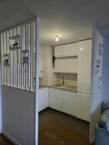 une cuisine avec des armoires blanches et un évier dans l'établissement Central, à Colombes