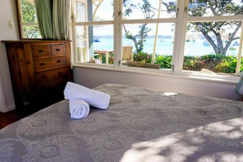 a bedroom with a bed with a pillow and a window at LAST ON THE STRAND, RUSSELL - The BOATHOUSE in Russell