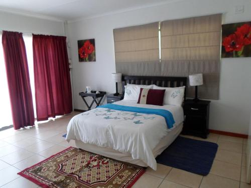 a bedroom with a large bed and red curtains at Buffalo View Lodge in East London