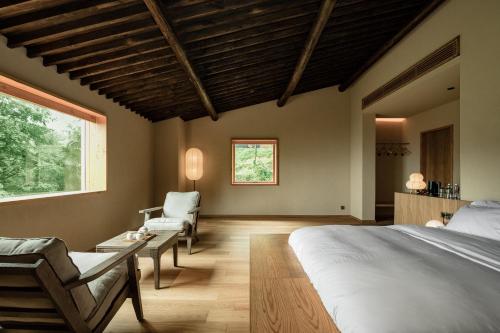 a bedroom with a large bed and a chair at 大山初里 Origin Villa Village Hotel&Resort in Tonglu
