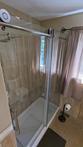 a shower with a glass door in a bathroom at Lovely Place in Kingston
