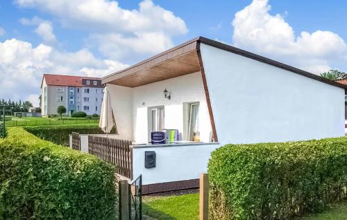 a small white house with a roof over a hedge at Ferienhaus Plau Am See in Kummerow