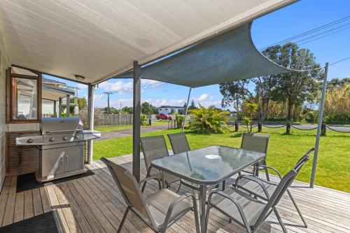a patio with a table and chairs and a grill at Bream Bay Sands - Ruakaka Holiday Home in Ruakaka