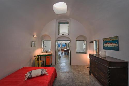 イアにあるOpuntia Traditional Cave Houseのベッドルーム(赤いベッド1台、デスク付)