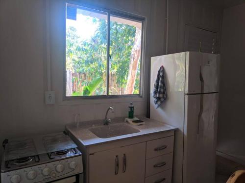 a kitchen with a white refrigerator and a window at Vila Contêiner - 900 m do centro in Morretes