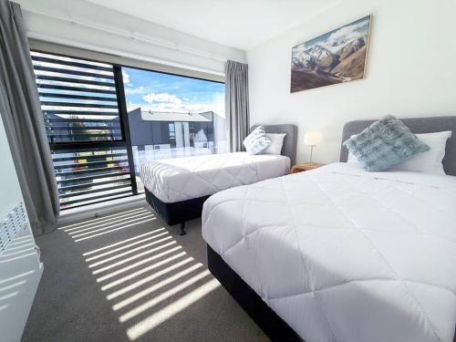 Un dormitorio con dos camas y una gran ventana. en The Best Value 2-bedroom Brand-new built townhouse, en Wanaka