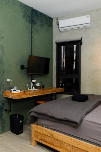 a bedroom with a bed and a desk with a computer at Lyn Urban by Atmosfera in Jepara