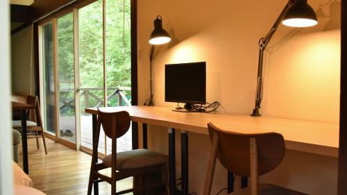a room with a desk with a monitor and chairs at HANOOTO Kitakarauizawa in Tsumagoi