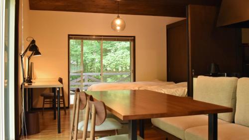 a room with a table and a bed and a window at HANOOTO Kitakarauizawa in Tsumagoi