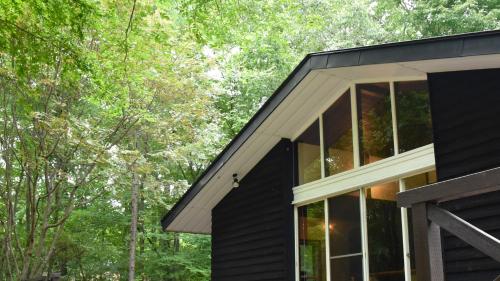 a black house in the woods with trees at HANOOTO Kitakarauizawa in Tsumagoi